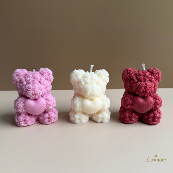 Heartfelt Rose Bear sculptural soy wax candle for romantic gifting and elegant home décor. Three teddy bear-shaped candles in pink, white, and red on a beige surface with a beige background.