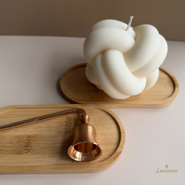 White knot-shaped candle on a wooden tray with a bronze candle holder on a neutral background, Lavanore brand visible. Knot sculptural soy wax candle designed for modern luxury home décor and gifting