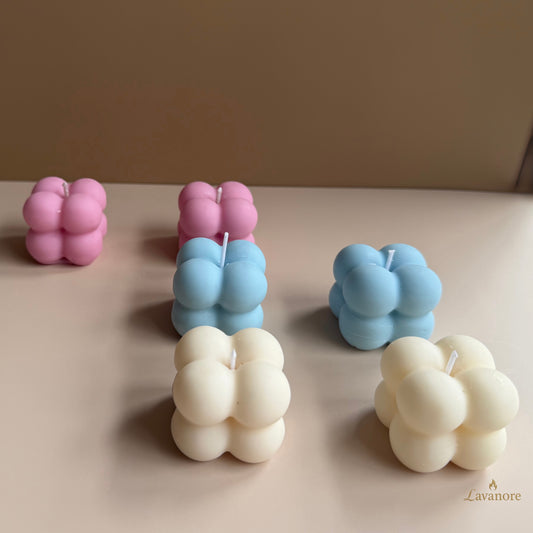 Set of bubble-shaped candles in pink, blue, and white on a beige surface with a neutral background. Lumi Bubble sculptural bubble soy wax candle for luxury gifting and modern home décor