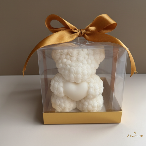 White rose teddy-shaped candle in a clear box with a gold ribbon on a neutral background.Heartfelt Rose Bear Grande sculptural soy wax candle for romantic gifting and home décor