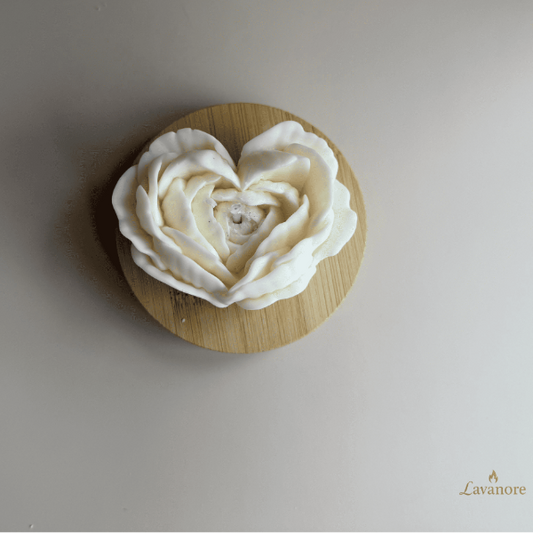 White rose-shaped object on a wooden base with 'Lavamore' branding. Heart in Bloom sculptural soy wax candle with layered petal design for luxury gifting. White rose-shaped object on a beige background with 'Lavanore' branding.