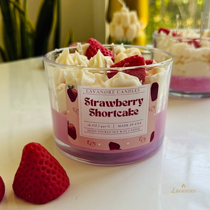 Strawberry Shortcake candle with whipped cream and strawberries on a white surface.