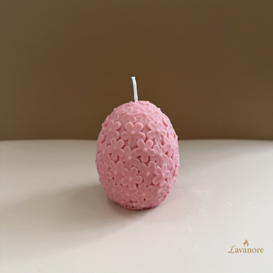 Pink textured candle on a beige surface with a brown background