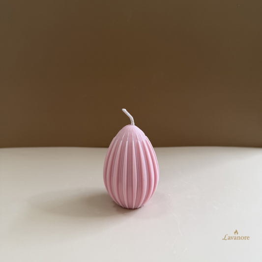 Pink ribbed candle on a beige surface with a brown background