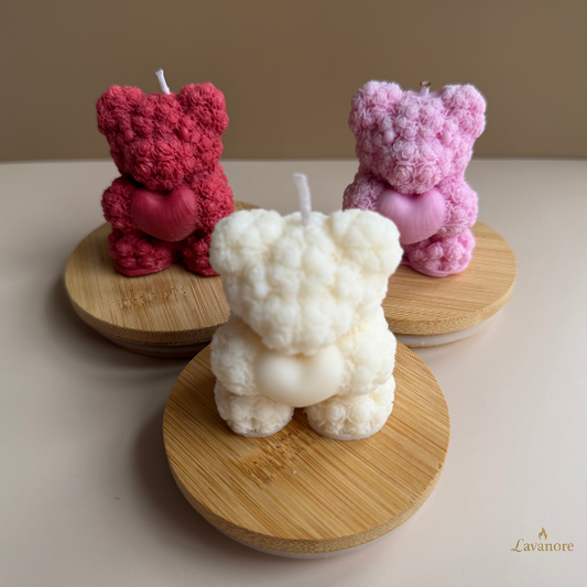 Heartfelt Rose Bear sculptural soy wax candle for romantic gifting and elegant home décor. Three bear-shaped candles in red, white, and pink on wooden stands with a beige background.