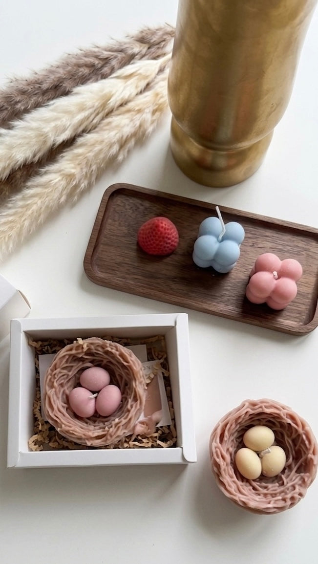 Decorative items including small nests with eggs on a wooden tray and white surface.