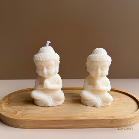Two Buddha-shaped candles on a wooden tray with a plain background Luxury Baby Buddha sculptural soy wax candle for meditation, home décor, and mindful gifting