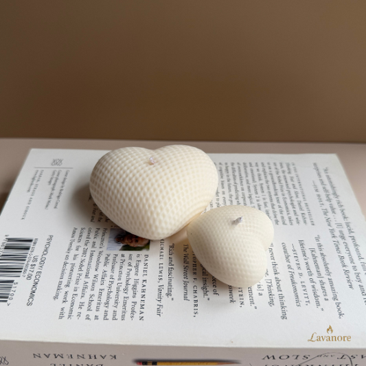 Two textured heart-shaped candles on an open book with a plain background. Heart sculptural soy wax candle designed for romantic gifting and elegant home décor