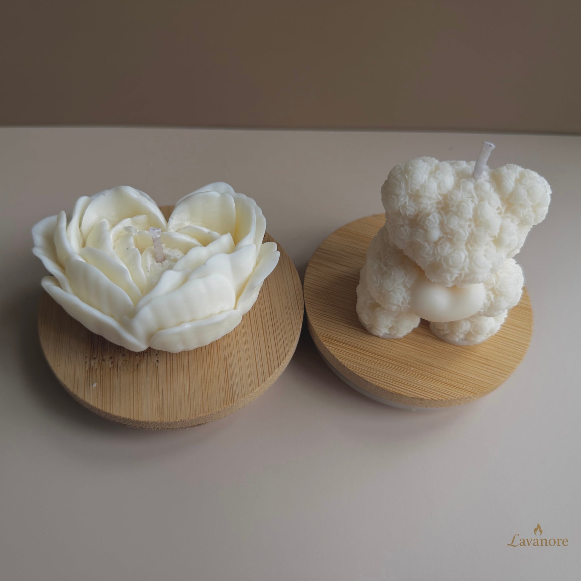 Rose Bear and rose heart sculptural soy wax candle set for Valentine’s gifting.
Two white candle sculptures, one flower-shaped and one resembling a teddy bear, on wooden bases with a plain background.