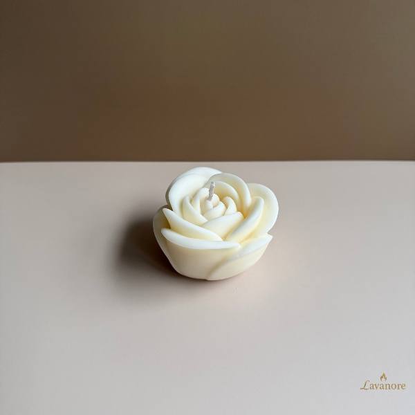 White rose-shaped candle on a beige surface with a brown background Rose Gift Box sculptural rose soy wax candle set of four for luxury gifting