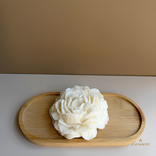 White flower-shaped candle on a wooden tray with a beige background.Peony Embrace sculptural peony soy wax candle for luxury gifting and home décor